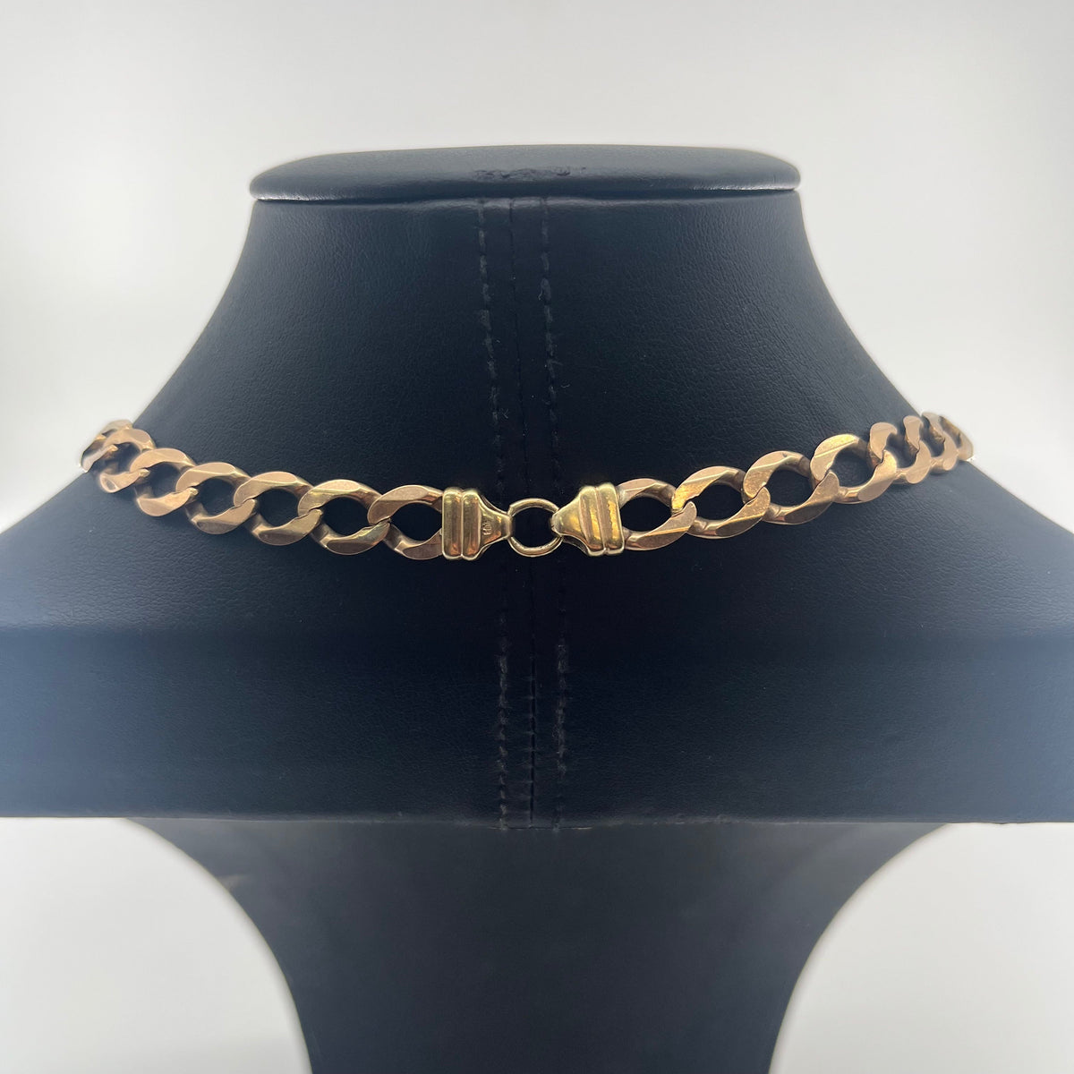 CB Stores 9ct yellow gold flat curb chain with oval links shown on a black display stand against a white background.
