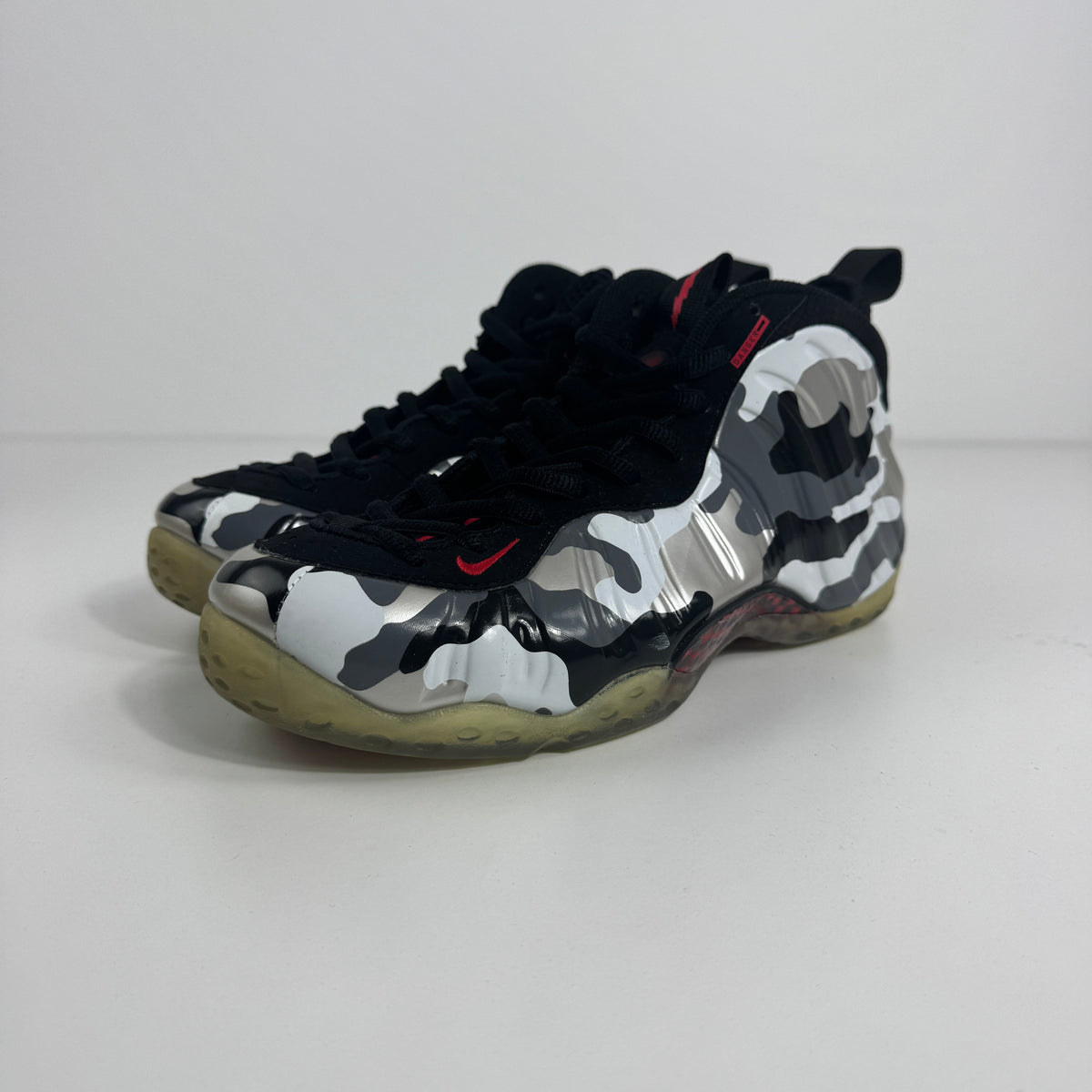 Nike Air Foamposite One PRM trainers in black, white and grey camo with translucent yellow soles on a plain white background.