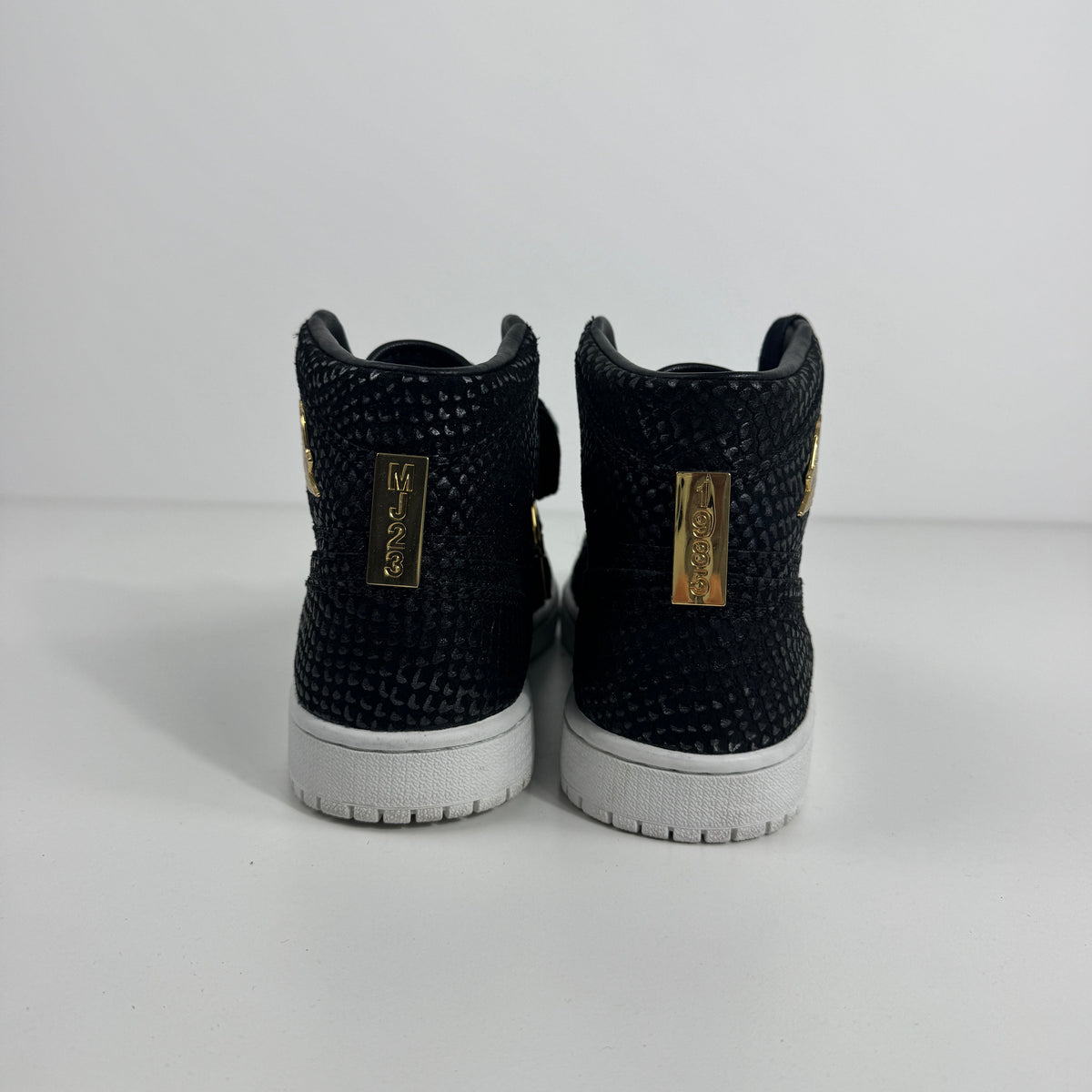 Black textured Nike high-top trainers with white soles and gold MJ23 tags on the heel, displayed against a white background.