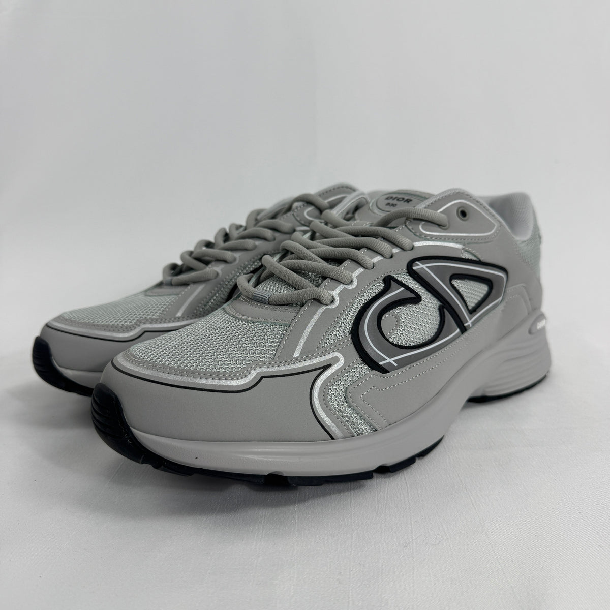 The Dior B30 Grey is a luxury sneaker featuring a technical mesh and microfiber upper in grey tones, with reflective