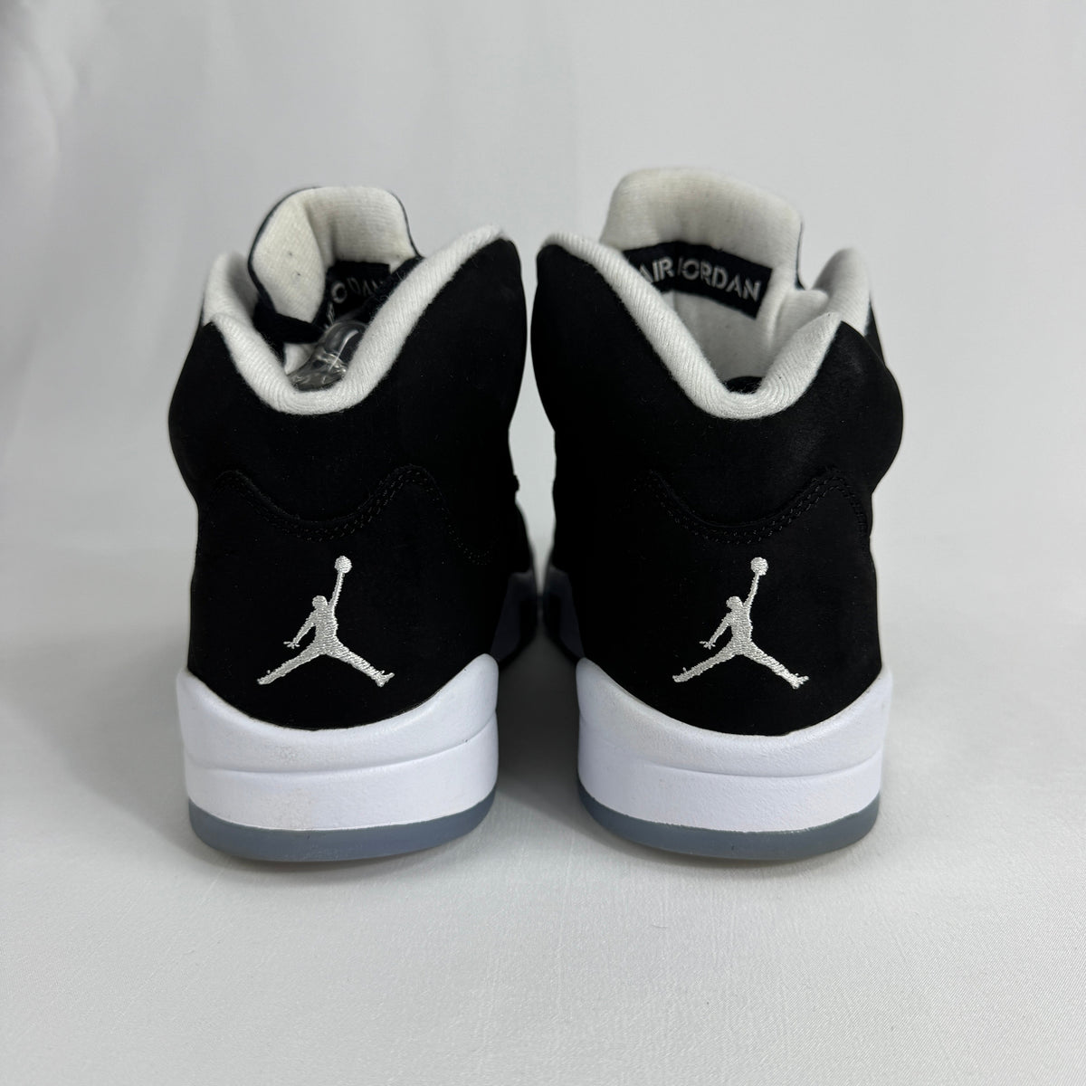 The Jordan 5 Retro Oreo is a classic basketball-inspired sneaker featuring a black nubuck upper, signature reflective