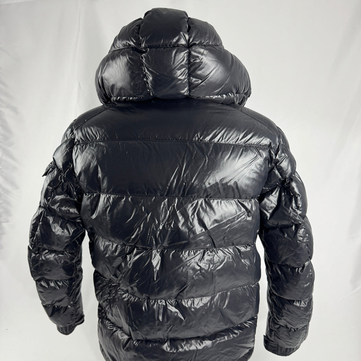The Moncler Maya jacket is a short, glossy down puffer known for its boxy fit, strong insulation, detachable hood, and