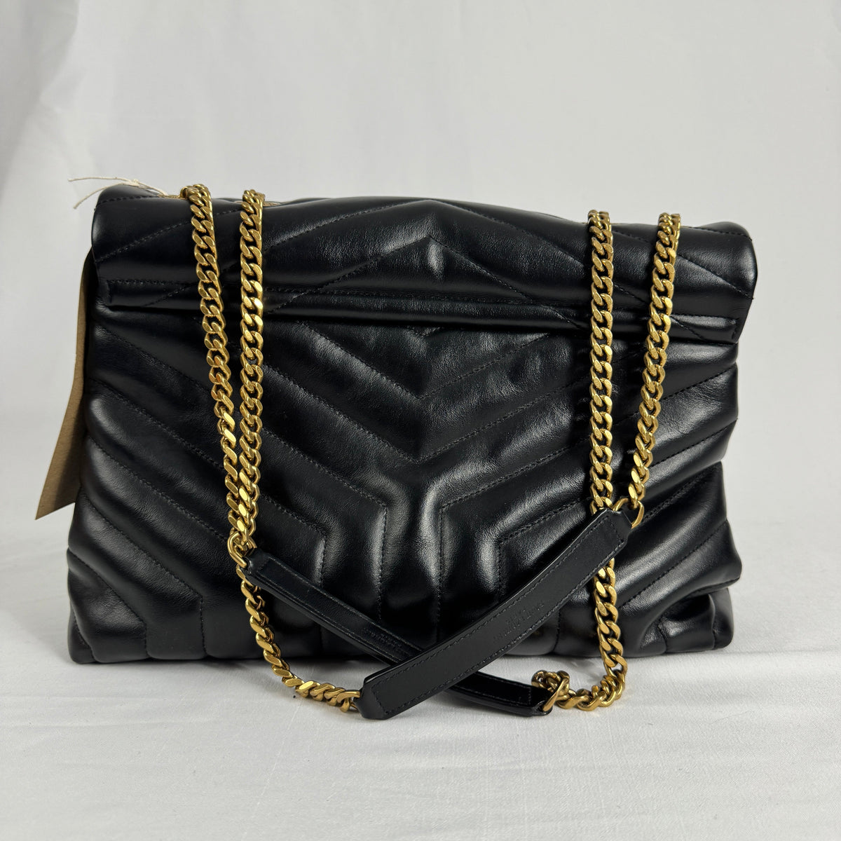 The Saint Laurent LouLou Crossbody Bag is a quilted leather handbag featuring the signature YSL logo, a chain strap, and a