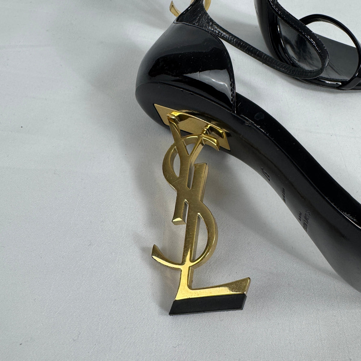 The Saint Laurent Opyum 110 is an iconic high-heel sandal renowned for its striking YSL logo heel. Crafted from premium