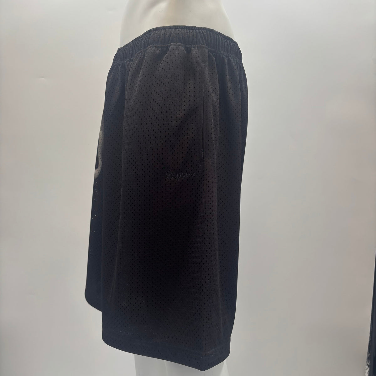Side view of a mannequin wearing SUPREME X Ghostface shorts with an elastic waistband and mesh fabric, on a light background.